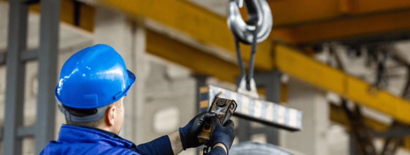 Operario controlando el pesaje de una bobina metálica con sistema de elevación en un entorno industrial, representando la fiabilidad en los sistemas de pesaje.